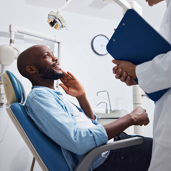 Man holding his cheek while talking to emergency dentist