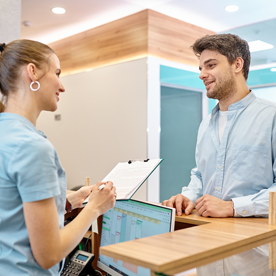 Man talking to receptionist at front desk of dental office