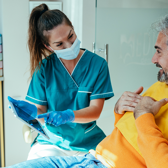 Dental team member showing a tablet screen to a patient