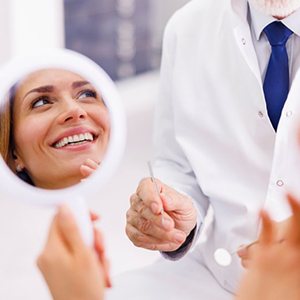 a patient checking her teeth with a mirror