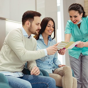 a couple receiving a brochure from a front desk member