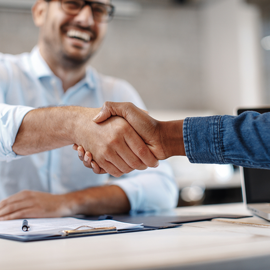Two people shaking hands across a desk