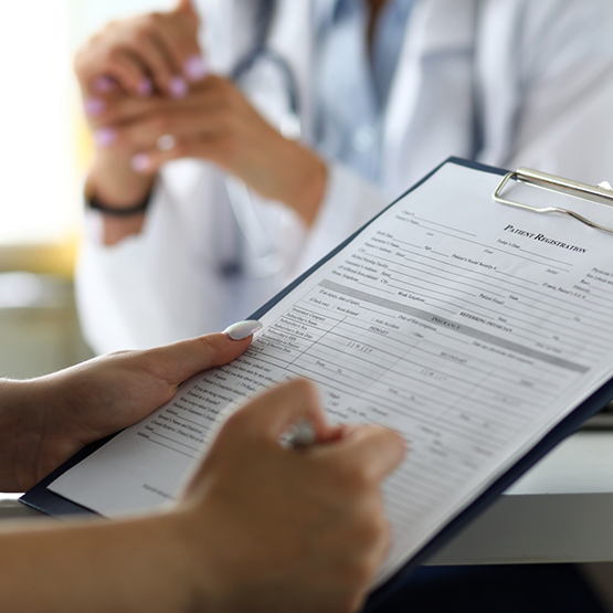 Person filling out a form on a clipboard in a dental office