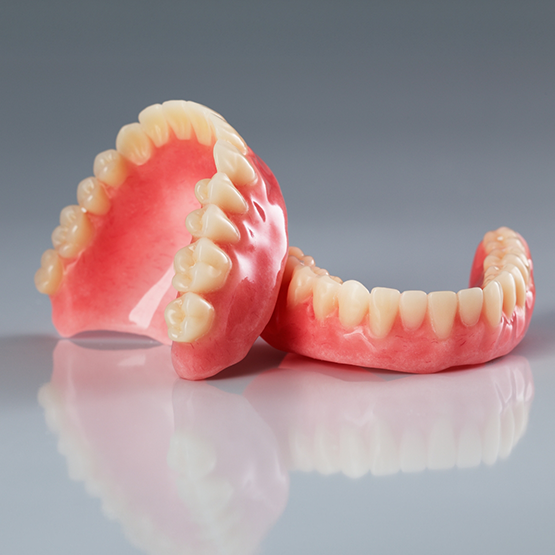 Set of full dentures resting on a light gray surface