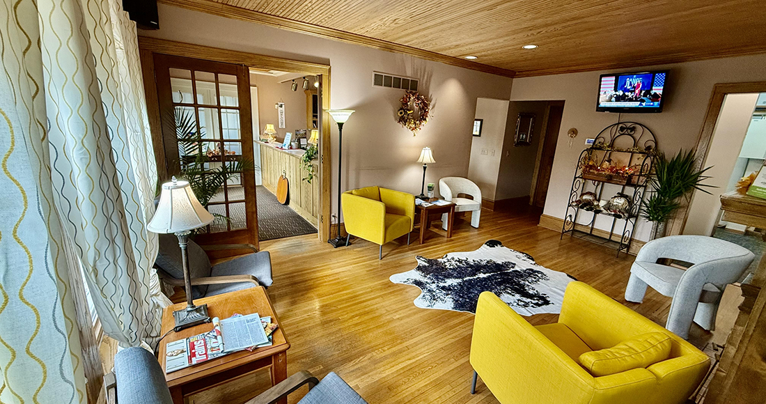 Dental office waiting area with hardwood floors and cozy decor