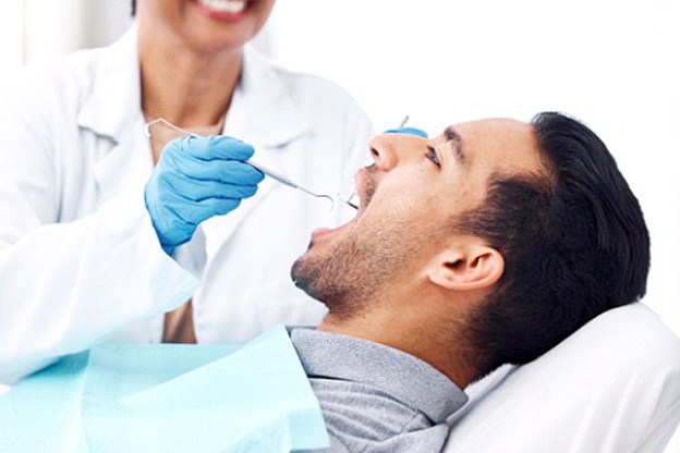Profile view of man in dental chair having teeth examined