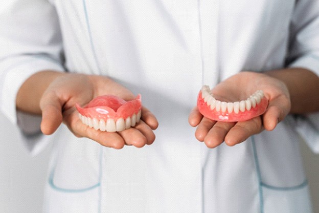 Hands holding complete arches of dentures