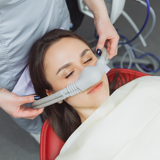 Woman relaxing in dental chair with mask over her nose for nitrous oxide sedation dentistry in Maplewood