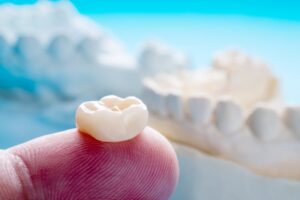 Person holding a dental crown on their finger